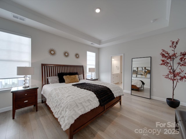 bedroom with a raised ceiling and light hardwood / wood-style flooring