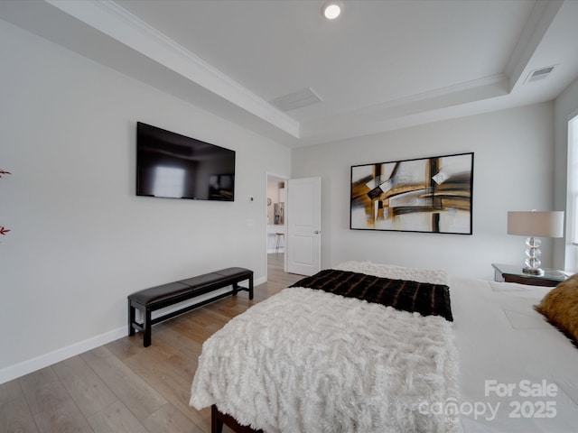 bedroom with wood-type flooring, a tray ceiling, and ornamental molding