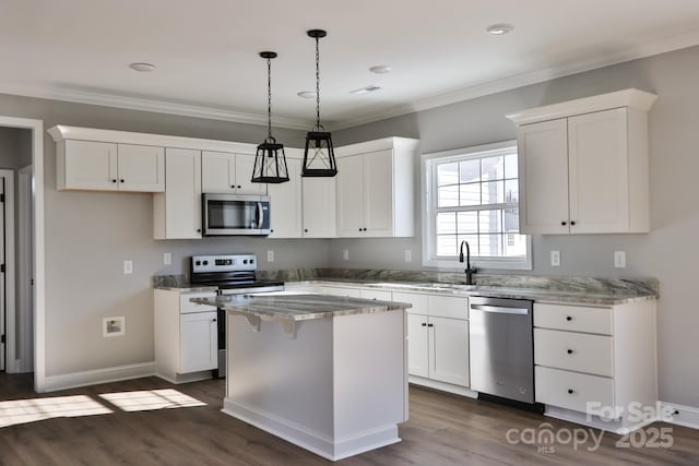 kitchen with a center island, appliances with stainless steel finishes, white cabinetry, and ornamental molding