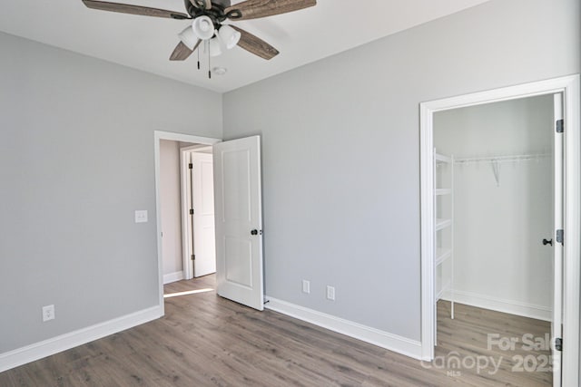 unfurnished bedroom with ceiling fan, dark hardwood / wood-style floors, a walk in closet, and a closet