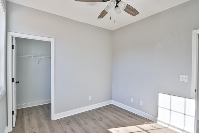 unfurnished bedroom with ceiling fan, a closet, a walk in closet, and light hardwood / wood-style flooring