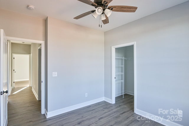 unfurnished bedroom featuring dark hardwood / wood-style flooring, ceiling fan, a closet, and a spacious closet