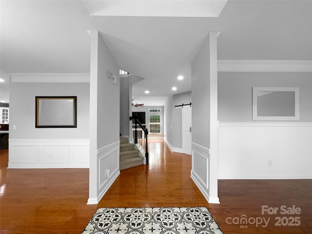 corridor featuring dark wood-style flooring, a barn door, stairway, and recessed lighting