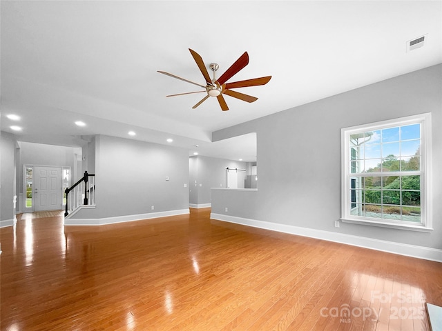 unfurnished living room featuring visible vents, stairway, baseboards, and wood finished floors