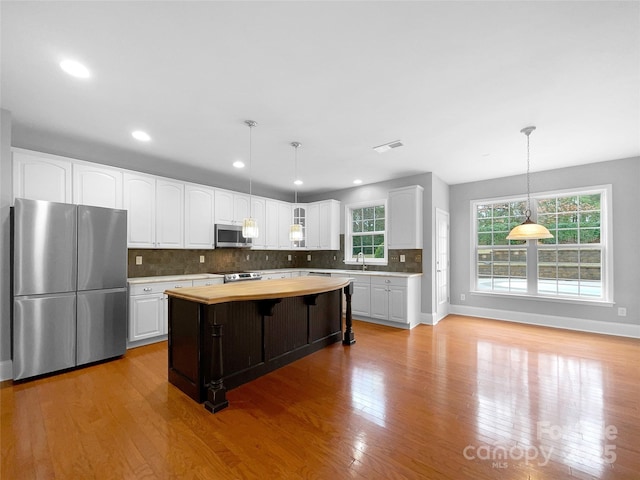 kitchen featuring white cabinets, a kitchen island, pendant lighting, and stainless steel appliances