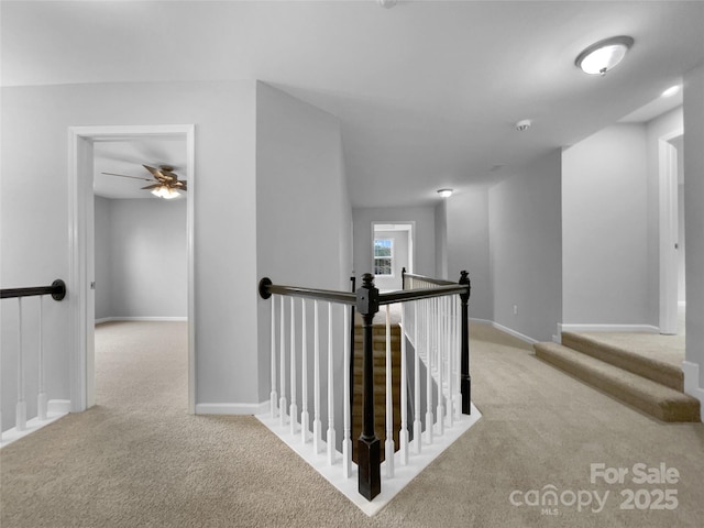 corridor featuring light carpet, baseboards, and an upstairs landing