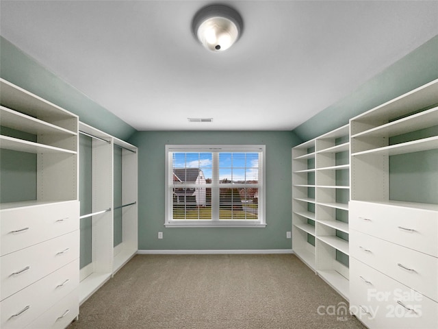 spacious closet featuring visible vents, vaulted ceiling, and light colored carpet