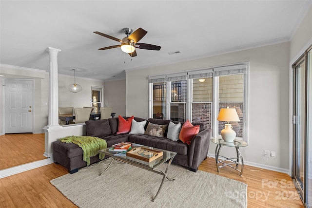 living room with ornate columns, visible vents, wood finished floors, and ornamental molding