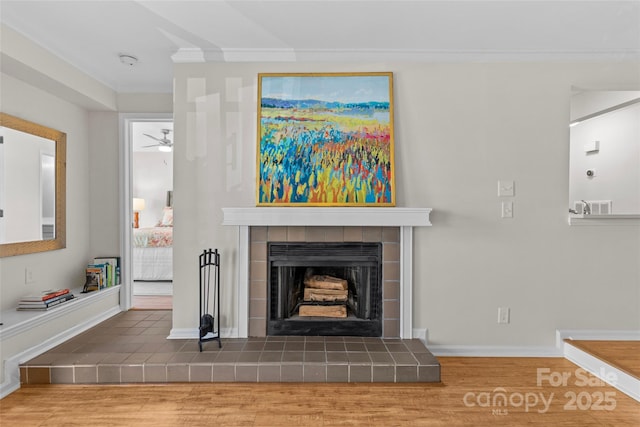 unfurnished living room with crown molding, a fireplace, baseboards, and wood finished floors