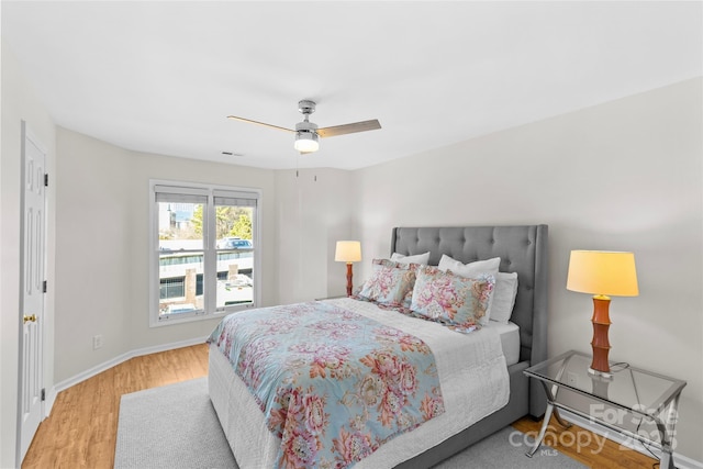 bedroom featuring ceiling fan, light wood-type flooring, visible vents, and baseboards