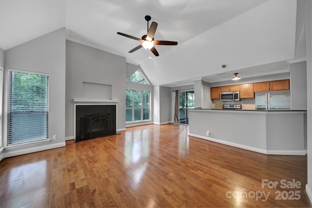 unfurnished living room with ceiling fan, ornamental molding, high vaulted ceiling, and light hardwood / wood-style flooring