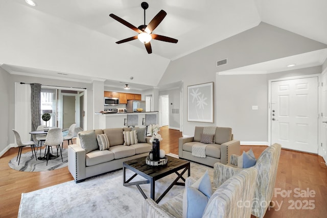 living room featuring high vaulted ceiling, ornamental molding, light hardwood / wood-style floors, and ceiling fan