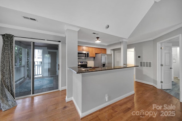 kitchen with light hardwood / wood-style flooring, stainless steel appliances, vaulted ceiling, and ornate columns