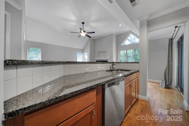 kitchen featuring sink, dishwasher, dark stone countertops, tasteful backsplash, and light hardwood / wood-style floors