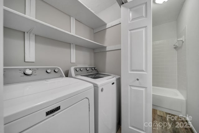 laundry area featuring hardwood / wood-style flooring and washing machine and clothes dryer