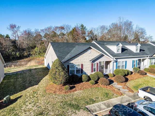 view of front of house featuring roof with shingles and a front yard