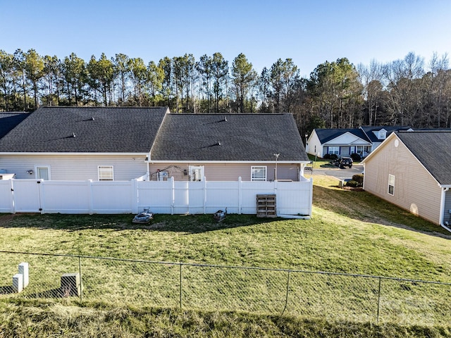 back of property featuring a fenced backyard, a lawn, and roof with shingles