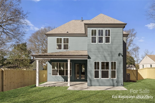 rear view of house featuring a patio, a lawn, a fenced backyard, and a shingled roof