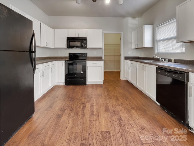 8353 Ainsworth St, Charlotte, NC 28216 - kitchen featuring dark countertops, light wood-type flooring, black appliances, white cabinetry, and a sink