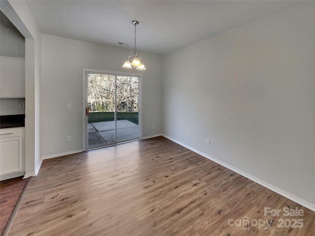 8353 Ainsworth St, Charlotte, NC 28216 - unfurnished dining area featuring light wood-type flooring, baseboards, and an inviting chandelier