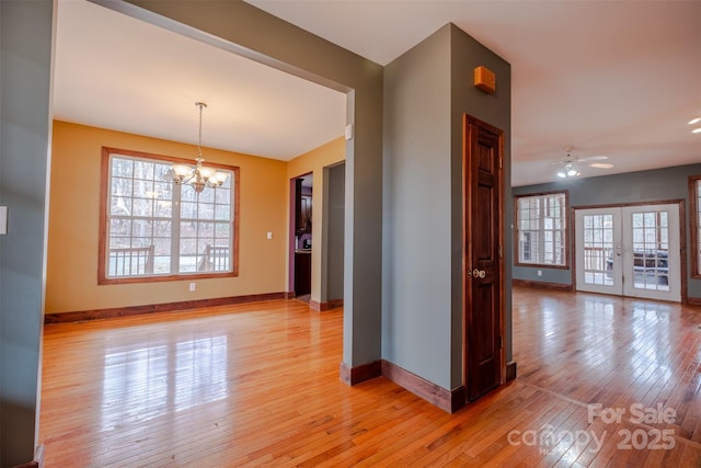 spare room featuring light wood finished floors, baseboards, and french doors