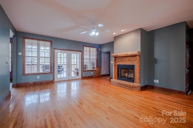 unfurnished living room with hardwood / wood-style flooring, baseboards, french doors, and a glass covered fireplace