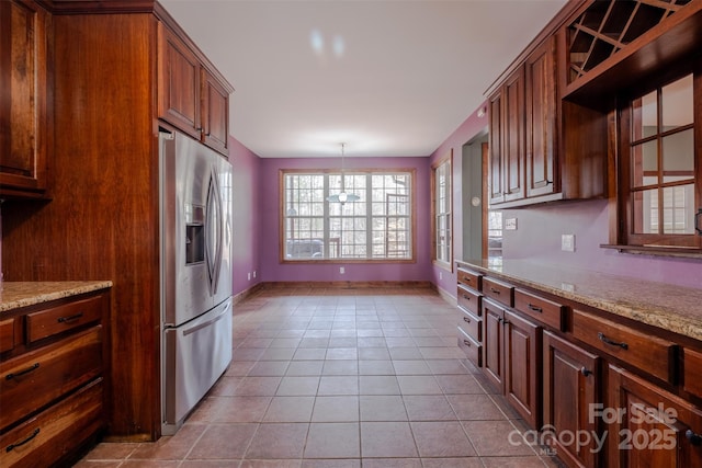 kitchen with baseboards, stainless steel refrigerator with ice dispenser, light tile patterned flooring, and light stone countertops