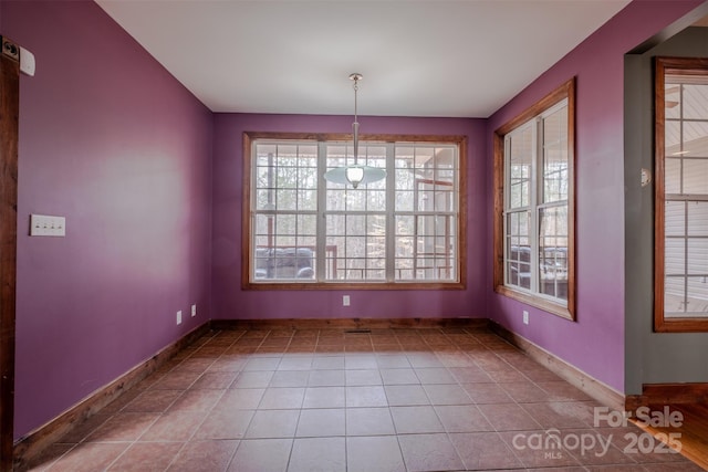 unfurnished dining area with tile patterned flooring and baseboards