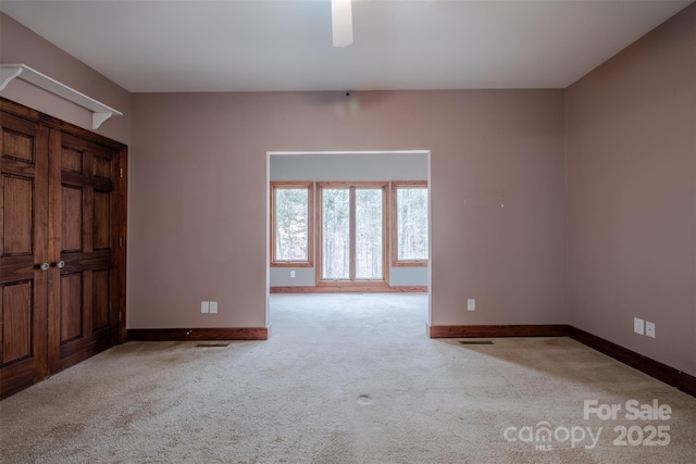 unfurnished room with baseboards and light colored carpet