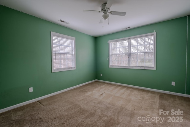 spare room featuring a wealth of natural light, carpet, and visible vents