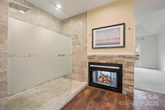 bathroom featuring hardwood / wood-style flooring, a shower, and a multi sided fireplace