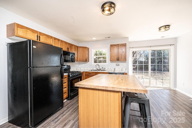 kitchen with a center island, sink, dark wood-type flooring, and black appliances