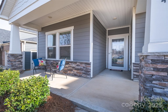 doorway to property with covered porch and stone siding