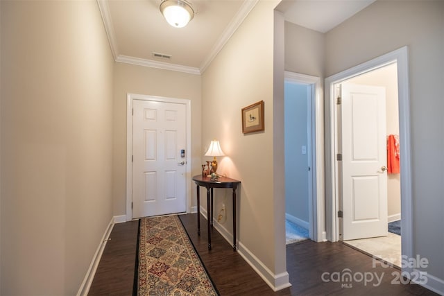 entryway with baseboards, dark wood-type flooring, visible vents, and crown molding