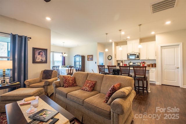 living room with recessed lighting, visible vents, dark wood finished floors, and an inviting chandelier