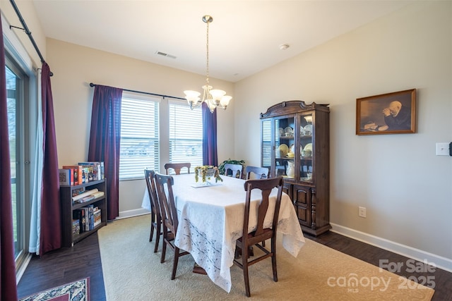 dining space with visible vents, baseboards, dark wood finished floors, and a notable chandelier