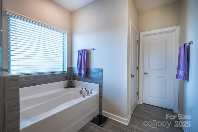 bathroom featuring a closet, baseboards, and a bath