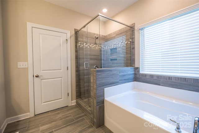 full bathroom with a stall shower, plenty of natural light, baseboards, and a bath