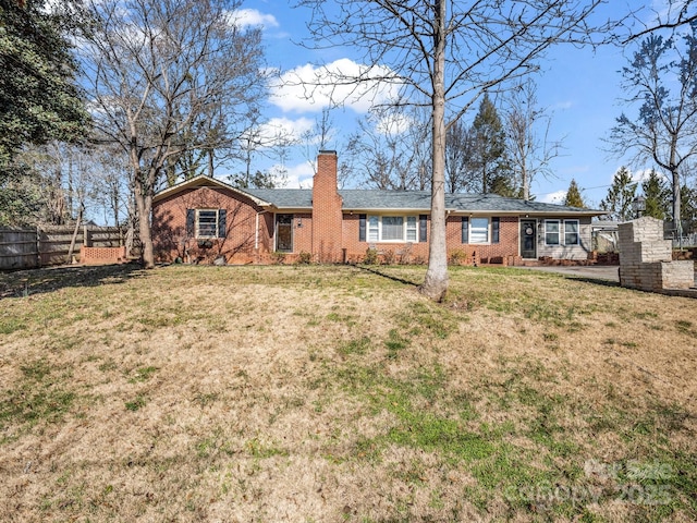 back of house featuring brick siding, fence, a chimney, and a lawn