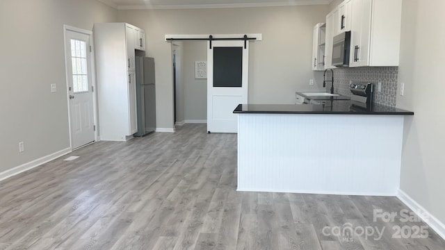 kitchen with stainless steel refrigerator, sink, white cabinets, kitchen peninsula, and a barn door