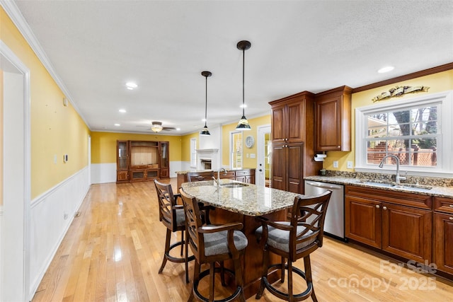 kitchen with a breakfast bar, dishwasher, light stone countertops, and sink