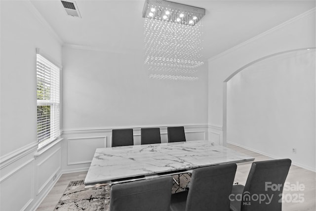 dining space featuring ornamental molding, an inviting chandelier, and light hardwood / wood-style floors