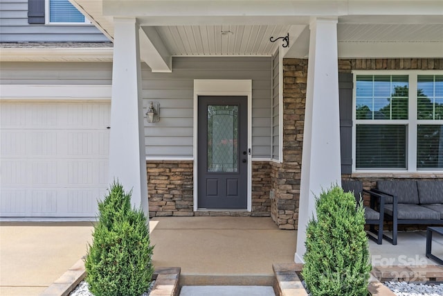 view of exterior entry with a garage and a porch