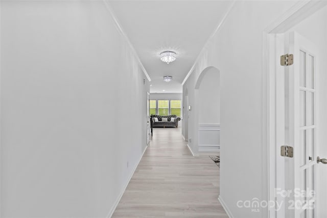 hallway with crown molding and light hardwood / wood-style flooring