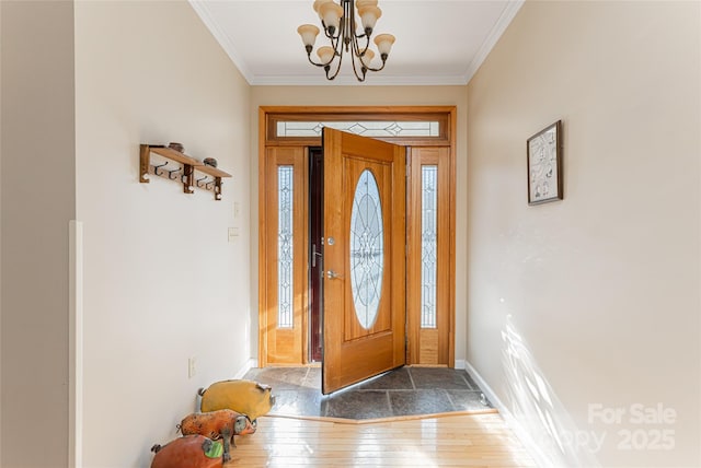 entryway featuring an inviting chandelier, baseboards, crown molding, and wood finished floors