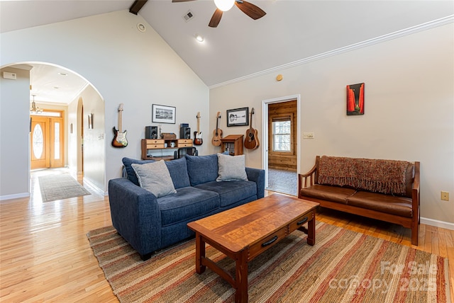 living area with arched walkways, beam ceiling, light wood finished floors, high vaulted ceiling, and baseboards