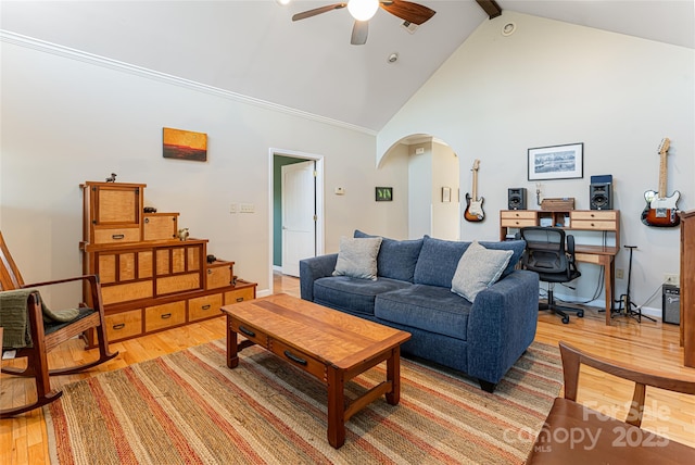 living area featuring arched walkways, high vaulted ceiling, light wood-style flooring, a ceiling fan, and beam ceiling