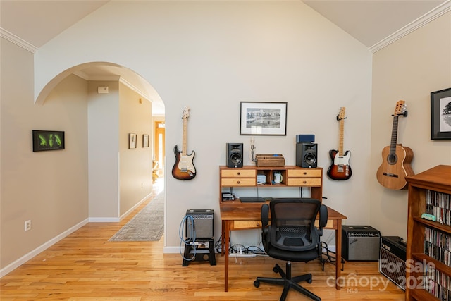 office featuring arched walkways, baseboards, vaulted ceiling, light wood finished floors, and crown molding