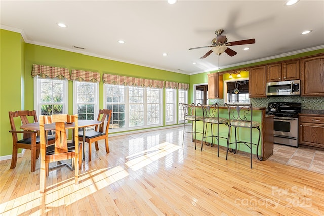 kitchen featuring stainless steel appliances, tasteful backsplash, dark countertops, and crown molding