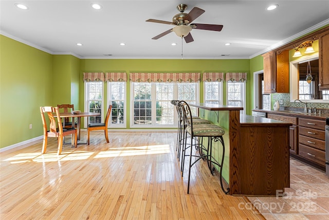 kitchen with plenty of natural light, ornamental molding, light wood finished floors, and dark countertops